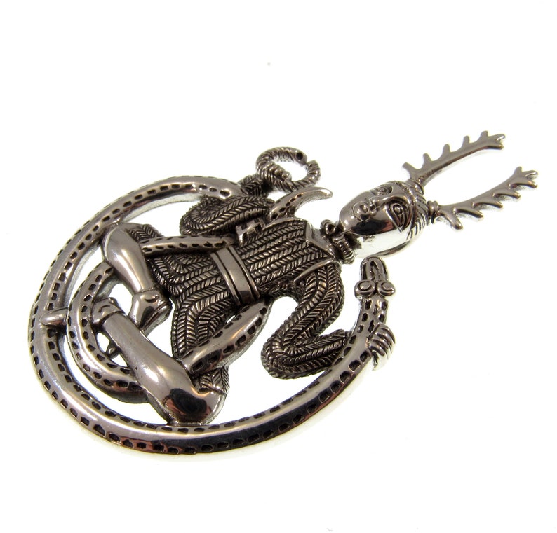 Pu&ograve; includere: Pendente in argento raffigurante una figura cornuta con un serpente avvolto attorno al suo corpo. La figura indossa un'armatura a maglia e ha un viso dettagliato.