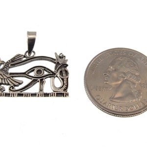 May include: Silver pendant featuring the Eye of Horus, an ancient Egyptian symbol of protection and good health. The pendant is about the size of a US quarter.