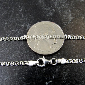 May include: A silver chain necklace with a lobster clasp. The chain is shown next to a US quarter for size comparison.