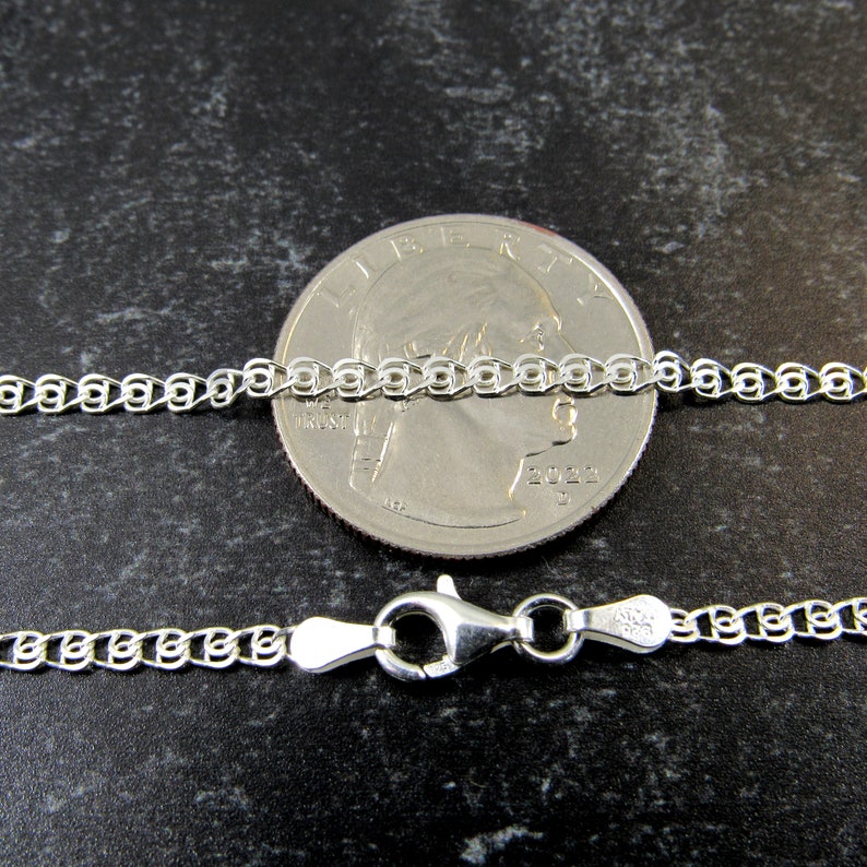 May include: A silver chain necklace with a lobster clasp. The chain is shown next to a US quarter for size comparison.