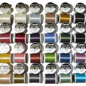 May include: A collection of thirty spools of Miyuki Beading Thread arranged in a grid. Each spool is labeled with the brand name, 330dtex, 100% nylon, and a unique color number. The threads feature a wide variety of solid colors including white, black, red, blue, green, yellow, pink, and metallic tones.