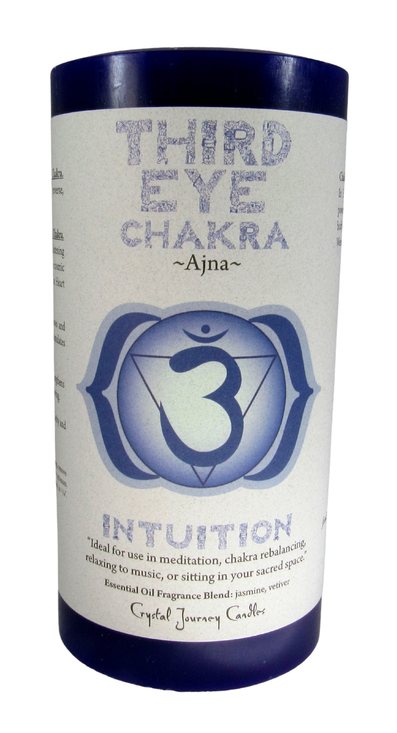 May include: A blue candle with a white label that says "Third Eye Chakra ~Ajna~" and features a blue and white symbol. The label also says "Intuition" and "Ideal for use in meditation, chakra rebalancing, relaxing to music, or sitting in your sacred space." The label also says "Essential Oil Fragrance Blend: jasmine, vetiver" and "Crystal Journey Candles."