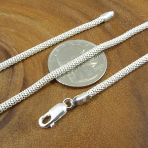 Op de afbeelding: Een zilveren ketting met een getextureerde afwerking. De ketting is ongeveer even breed als een Nederlandse tien-cent munt.