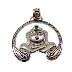 May include: Silver pendant featuring an Egyptian queen design. The pendant has a detailed face with a green gemstone accent and is suspended from a decorative bail. The pendant is set within a circular frame with intricate patterns.