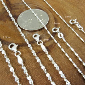 May include: Close-up of several silver chain necklaces with different thicknesses, ranging from 1mm to 2.3mm. Each chain is shown with its clasp and measurement. A US quarter coin is included for size comparison.