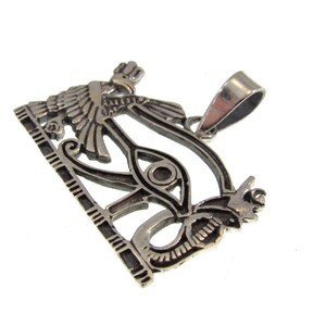 May include: Silver pendant featuring the Eye of Horus, a symbol of protection and good health in ancient Egyptian mythology. The pendant depicts the eye within a winged serpent, with a detailed design and intricate carvings.