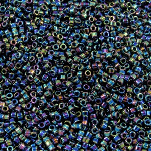 Op de afbeelding: Een close-up van een grote hoeveelheid iriserende blauwe en groene zaad kralen. De kralen zijn klein en rond, met een metallic afwerking.