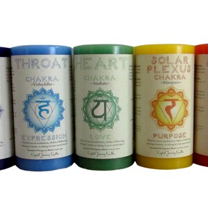 May include: Seven chakra candles, each with a different color and symbol. The candles are labeled with the name of the chakra, the Sanskrit symbol, and the corresponding chakra benefit. The colors are red, orange, yellow, green, blue, indigo, and violet.