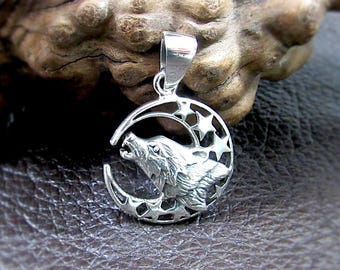 Könnte beinhalten: Ein silberner Anhänger mit einem heulenden Wolf in einem Halbmond mit Sternaussparungen. Der Anhänger hat ein detailliertes Design und eine Öse für eine Kette. Der Schmuck ist wahrscheinlich aus Sterlingsilber und für den Alltag geeignet.