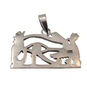 May include: Silver pendant featuring an intricate cutout design of an eye with wings. The back of the pendant is stamped with "925", indicating it is made of sterling silver.