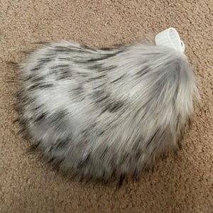 May include: A fluffy gray and black faux fur tail with a white elastic band.