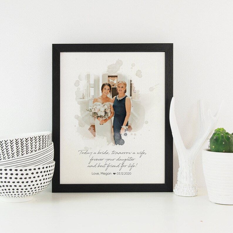 May include: A framed photograph of a bride and her mother, with a watercolour effect. The photo is surrounded by a black frame. The text below the photo reads: "Today a bride, tomorrow a wife, forever your daughter and best friend for life! Love, Megan 03.12.2020"