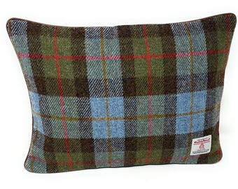 Op de afbeelding: Een rechthoekig sierkussen met een groen, bruin en lichtblauw ruitpatroon met dunne rode en gele accentlijnen. Het kussen is voorzien van een donkerbruine bies en een wit Harris Tweed-label dat in de rechterbenedenhoek is genaaid.