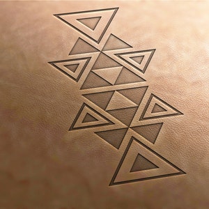 Puede incluir: Primer plano de una superficie de cuero marrón claro con un diseño geométrico. El diseño está compuesto por triángulos interconectados, creando un patrón simétrico. Los triángulos son de un tono marrón más oscuro.