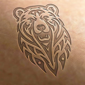 Könnte beinhalten: Ein detailliertes Linienkunstdesign eines Bärenkopfes mit komplizierten Mustern und einem wilden Ausdruck. Das Design ist in eine braune Lederoberfläche geschnitten.