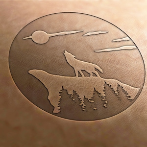 Könnte beinhalten: Ein braunes Lederoval mit einem geprägten Design eines heulenden Wolfs auf einem Berg, vor Sonne und Wolken. Der geprägte Entwurf erzeugt einen texturierten Effekt. Das Bild zeigt Natur und Wildtiere.