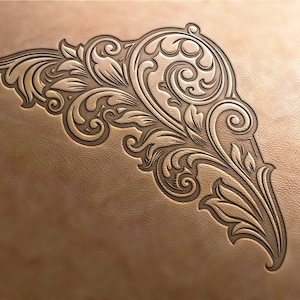 May include: Intricate floral design carved into a piece of leather. The design features swirling leaves and vines, creating a decorative and elegant pattern.
