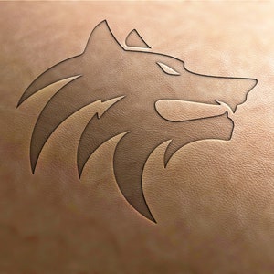 May include: A stylized wolf head design carved into a light brown leather surface.