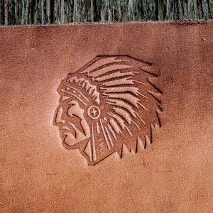 Peut inclure: Un portefeuille en cuir marron avec un motif gaufré représentant un chef amérindien portant une coiffe.