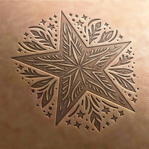 May include: A detailed, intricate star design carved into a piece of leather. The star is surrounded by a circular pattern of leaves and small stars.