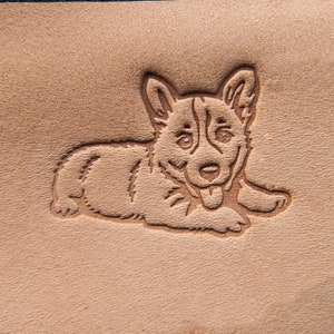 Puede incluir: Un parche de cuero marrón con un diseño estampado de un perro de dibujos animados con la lengua fuera.