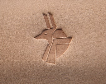 May include: A brown leather surface with a stylized image of an anubis head embossed into the surface.