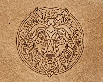 Op de afbeelding: Een gedetailleerde lijntekening van een wolfskop in een cirkelvormig frame met ingewikkelde ontwerpen. De ogen van de wolf zijn wijd open en het ontwerp is in bruin op een lichtbruine achtergrond.