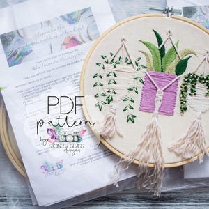 a hand-embroidered piece of art with a plant design, displayed alongside a printed pattern and instructions for creating the embroidery.