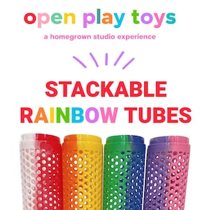 May include: Four colorful stackable rainbow tubes. The tubes are red, orange, yellow, green, blue, and pink. The tubes have a honeycomb design and the text "open play toys" and "STACKABLE RAINBOW TUBES".