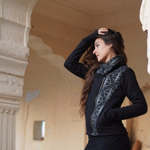 以下が含まれることがあります： 左側に銀と黒の模様が施された黒いジッパー付きジャケット。ジャケットはハイネックでジッパーで閉じられます。