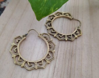 May include: A pair of gold hoop earrings with a geometric design. The earrings are made of metal and have a circular shape.