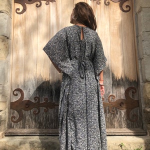 May include: A black and white floral print maxi dress with a long, flowing skirt and a tie at the back.