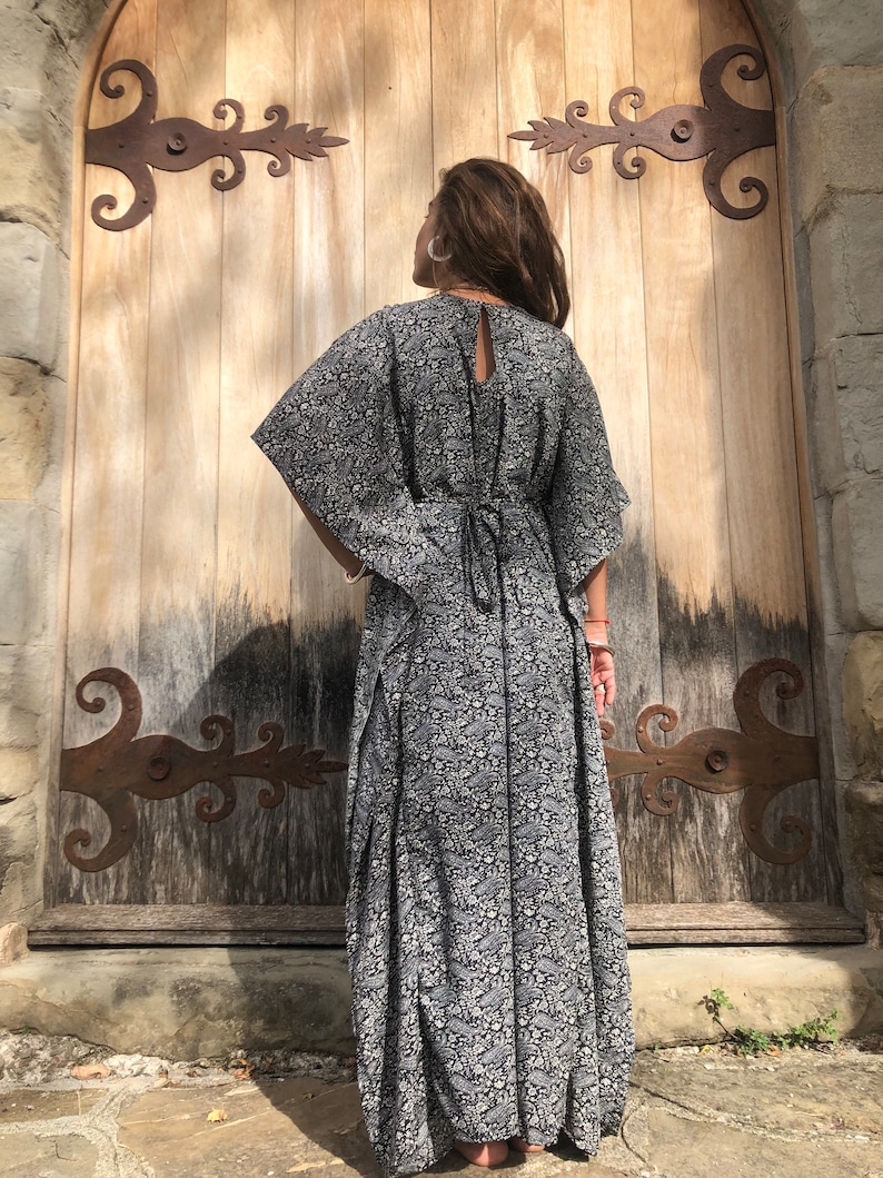 May include: A black and white floral print maxi dress with a long, flowing skirt and a tie at the back.