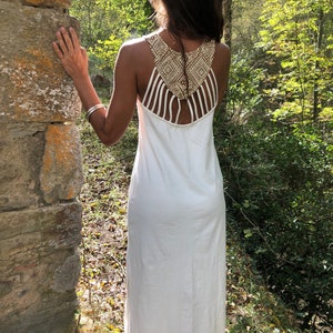 Peut inclure: Robe maxi blanche avec un motif géométrique au dos. La robe est sans manches et ample.