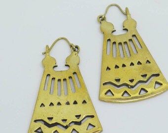 May include: A pair of gold-toned earrings with a geometric design. The earrings are shaped like a triangle with a cutout pattern of lines and triangles.