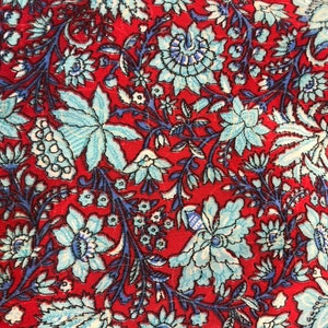May include: Red fabric with a blue and white floral pattern. The fabric has a vintage feel and is perfect for crafting projects.