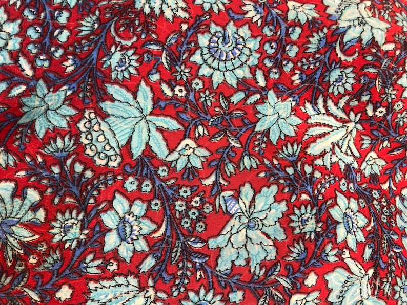 May include: Red fabric with a blue and white floral pattern. The fabric has a vintage feel and is perfect for crafting projects.