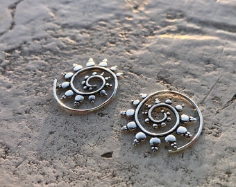 May include: A pair of silver spiral earrings with a beaded design. The earrings are made of metal and have a circular shape.