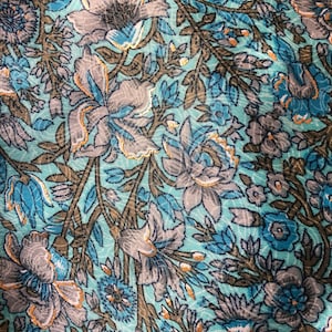 May include: A close-up of a teal fabric with a floral pattern. The flowers are in shades of blue, gray, and brown. The fabric has a subtle sheen.