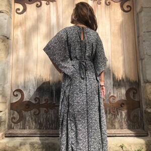 May include: A black and white floral print maxi dress with a long, flowing skirt and a tie at the back.