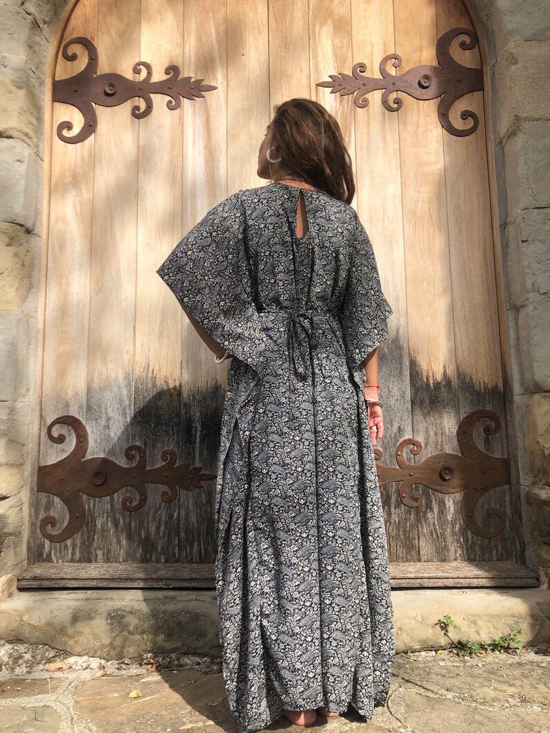 May include: A black and white floral print maxi dress with a long, flowing skirt and a tie at the back.