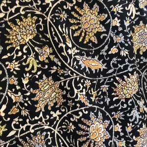 May include: Black fabric with a white and gold floral pattern. The pattern features intricate swirls and leaves.