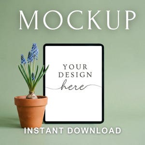 May include: A digital tablet mockup with the text "MOCKUP" at the top and "INSTANT DOWNLOAD" at the bottom. The tablet displays "YOUR DESIGN here" and is next to a potted plant with blue flowers. The background is a solid green color.