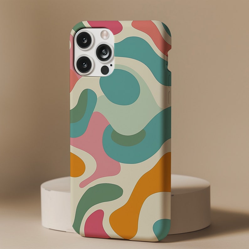 Pu&ograve; includere: Una custodia per telefono bianca con un design astratto colorato con forme rosa, blu, verdi e arancioni. La custodia ha un ritaglio per l'obiettivo della fotocamera.