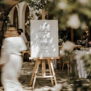 May include: A white welcome sign with black text on an easel. The sign reads "Welcome to the wedding of Henrietta Mitchell and Richard Sanchez, March 12th, 2023. Thank you for celebrating with us!"