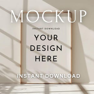 May include: A framed art mockup with the word "MOCKUP" at the top. The text "INSTANT DOWNLOAD" appears above and below the words "YOUR DESIGN HERE". The frame is a light brown color, and the background is a neutral beige.