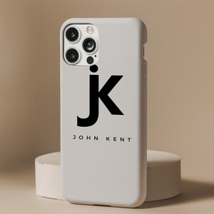 Pu&ograve; includere: Custodia bianca per iPhone con una lettera "J" nera e il testo "JOHN KENT" stampato sul retro.
