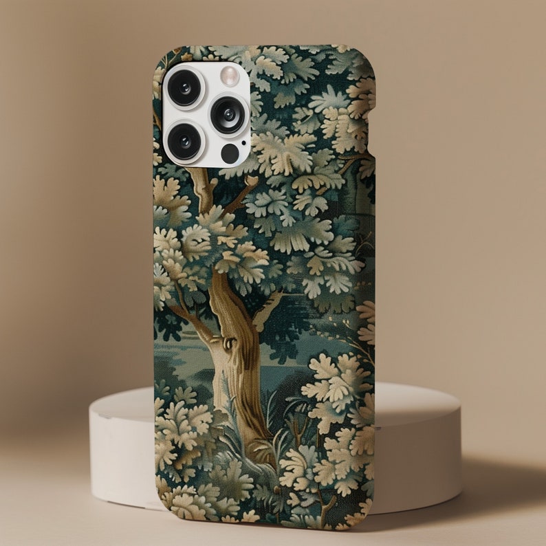 Pu&ograve; includere: Una custodia per telefono con un design di arazzo vintage che presenta un grande albero con foglie verdi e blu. La custodia ha un ritaglio per la fotocamera con tre obiettivi.