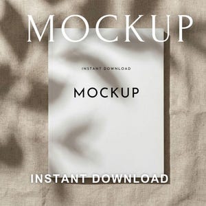 Puede incluir: Una maqueta rectangular blanca con la palabra «MOCKUP» en una fuente grande y elegante. Las palabras «INSTANT DOWNLOAD» aparecen arriba y abajo del texto principal. El fondo es una tela beige neutra con sombras sutiles.