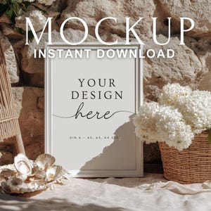 May include: A white framed mockup with the text "MOCKUP INSTANT DOWNLOAD" at the top. The frame has the text "YOUR DESIGN here" in the center. A wicker basket with white flowers and seashells are in the foreground.
